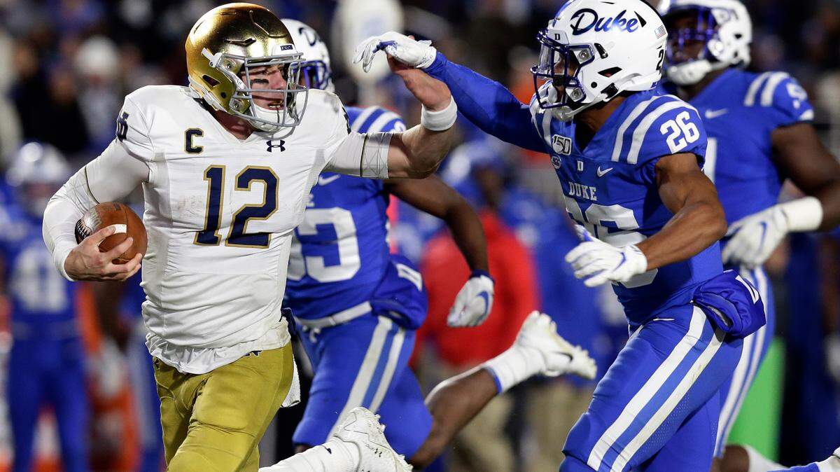 Notre Dame quarterback Ian Book (12) runs the ball while Duke safety Michael Carter II (26) chases during their game in Durham, N.C., Saturday, Nov. 9, 2019.