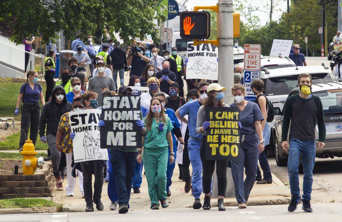 A group of counter-protesters walk towards the North Carolina Legislative Building during a Reopen NC rally in downtown Raleigh Tuesday, April 28, 2020. Protesters were calling for Gov. Roy Cooper to end the restrictions put in place because of the coronavirus pandemic.