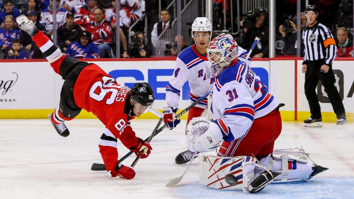 New York Rangers goaltender Igor Shesterkin (31) defends his net as New Jersey Devils center Jack Hughes (86) falls to the ice during the second period in game seven of the first round of the 2023 Stanley Cup Playoffs at Prudential Center.