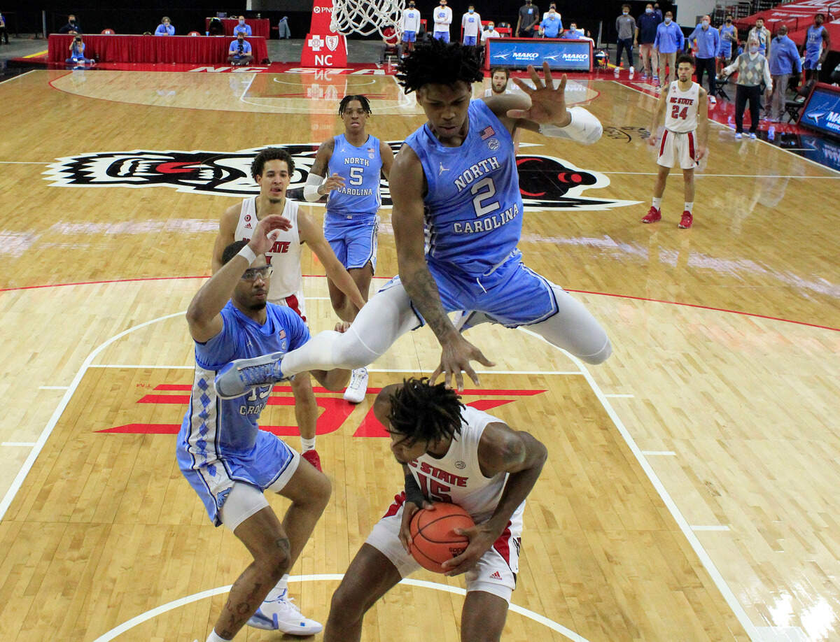North Carolina’s Caleb Love (2) leaps to avoid N.C. State’s Manny Bates (15) during N.C. State’s 79-76 victory over UNC at PNC Arena in Raleigh, N.C., Tuesday, December 22, 2020.