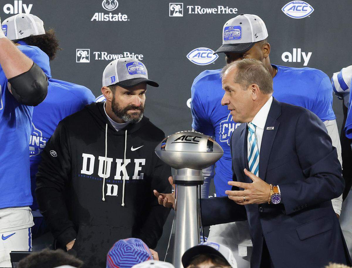 Duke head coach Manny Diaz talks with ACC Commissioner Jim Phillips prior to the trophy presentation after the Blue Devils’ 27-20 overtime win over Virginia in the ACC Football Championship on Saturday, Dec. 6, 2025, at Bank of America Stadium in Charlotte, N.C.