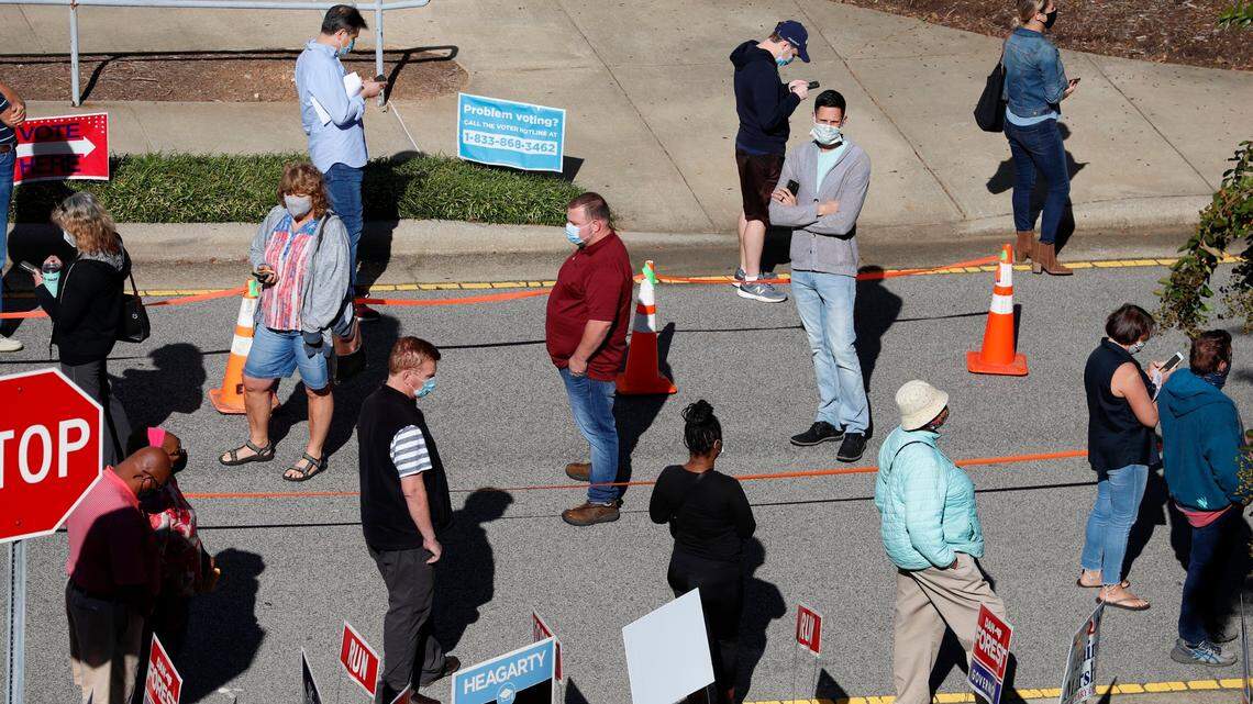 Voters wait in line outside the Herbert C. Young Community Center in Cary, N.C. on the first day of early voting Thursday, Oct. 15, 2020.