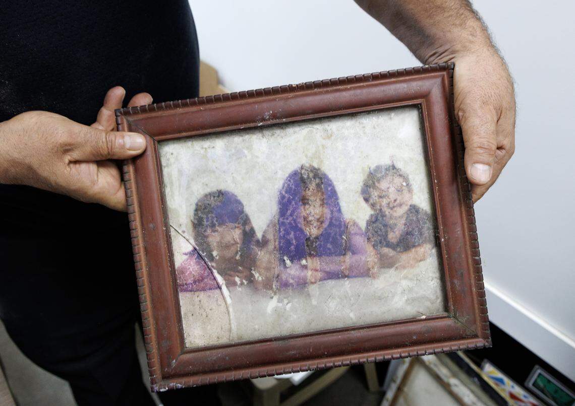 Mediterranean Deli owner Jamil Kadoura, photographed on Thursday, Sept. 4, 2025, in Chapel Hill, N.C. holds a photograph of his children that was damaged in a July 2023 fire at the restaurant. The restaurant will reopen on Tuesday.