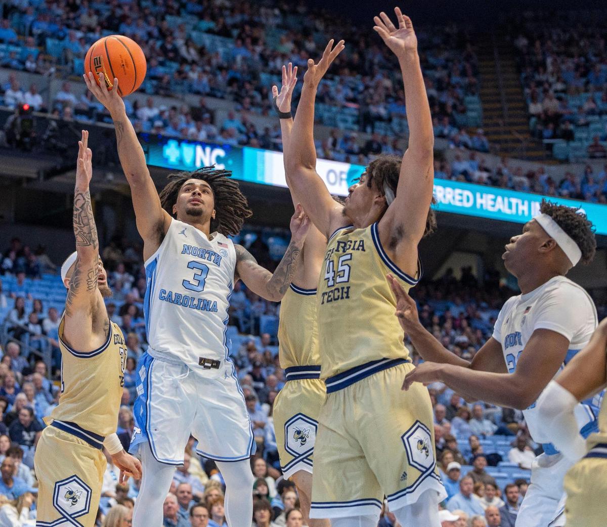 North Carolina guard Elliot Cadeau (3) drives to the basket against Georgia Tech’s Duncan Powell (31) and Dorian Onwuchekwa (45) in the first half on Saturday, December 7, 2024 at the Smith Center in Chapel Hill, N.C.