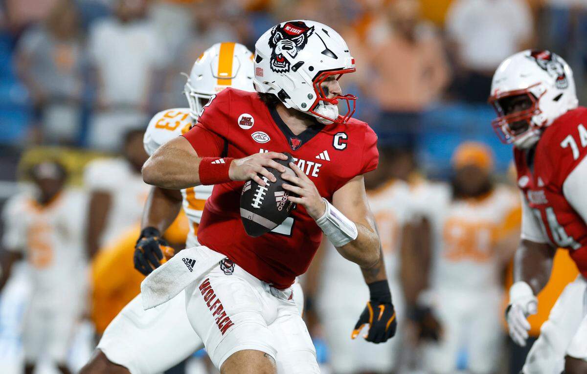 N.C. State quarterback Grayson McCall (2) scrambles away from the pressure by Tennessee defensive lineman Daevin Hobbs (53) during the second half of Tennessee’s 51-10 victory over N.C. State in the Duke’s Mayo Classic at Bank of America Stadium in Charlotte, N.C., Saturday, Sept. 7, 2024.