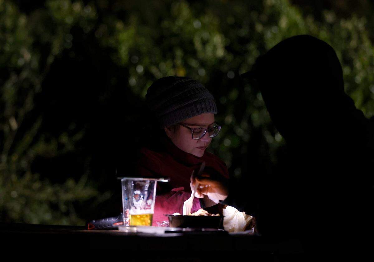 Molly Papp and James Childers eat by the light of a cell phone and flashlight at Red’s Corner during the Moore County power outage on Monday, Dec. 5, 2022, in Southern Pines, N.C.