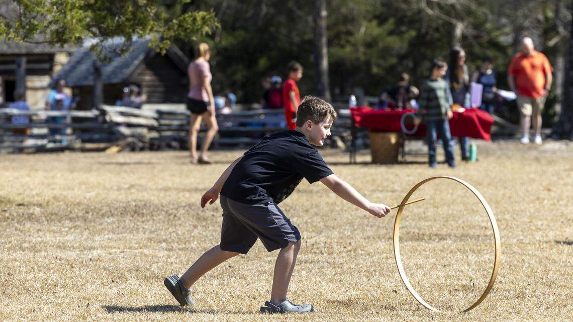 Aaron Smith, 9, a homeschooler from Durham, plays with a hoop-and-stick toy, a colonial-era game, during a homeschool day event at Bennett Place State Historic Site in Durham on Friday.