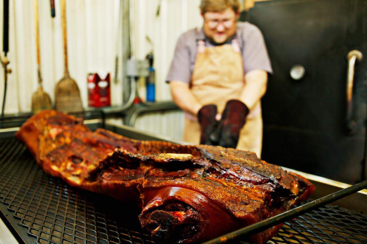 Wood-smoked barbecue is removed from the smoker by barbecue man and Picnic owner Wyatt Dickson.