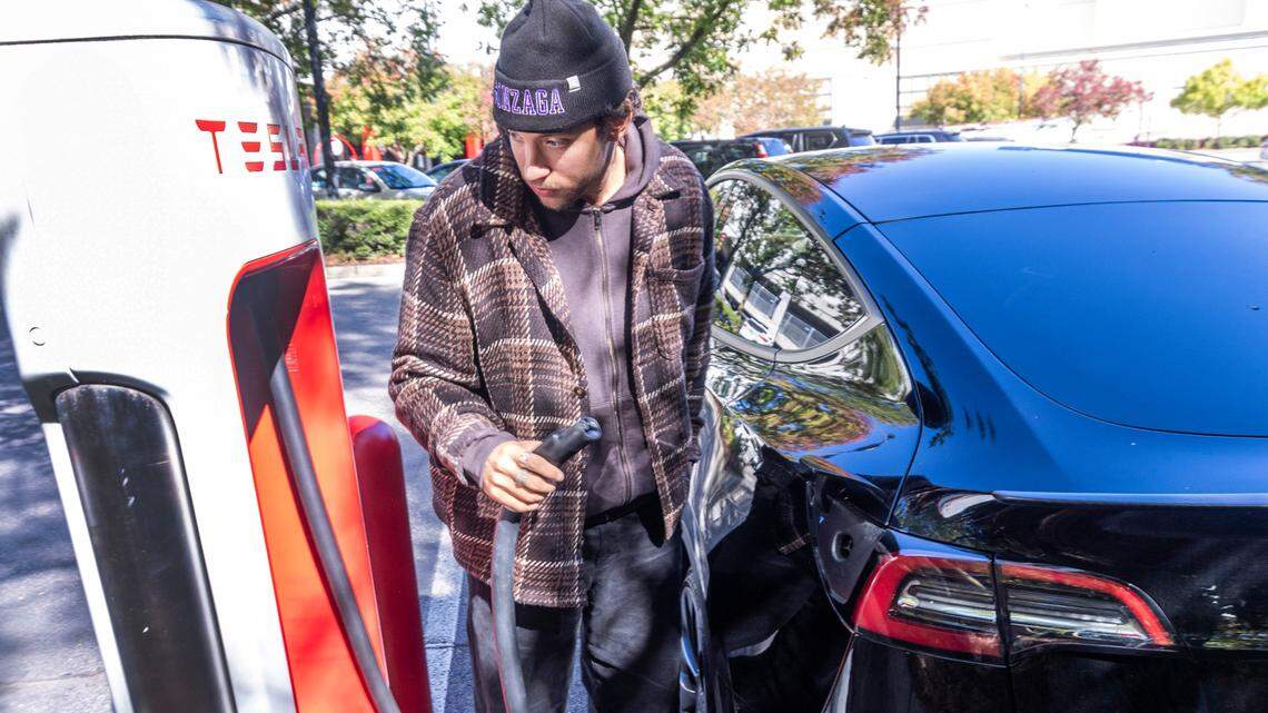 Max Fisher finishes charging his mother’s Model Y Tesla at an electric charging station at North Hills in Raleigh Tuesday, October. 17, 2023. Electric vehicle owners will see an increase in annual registration fees.
