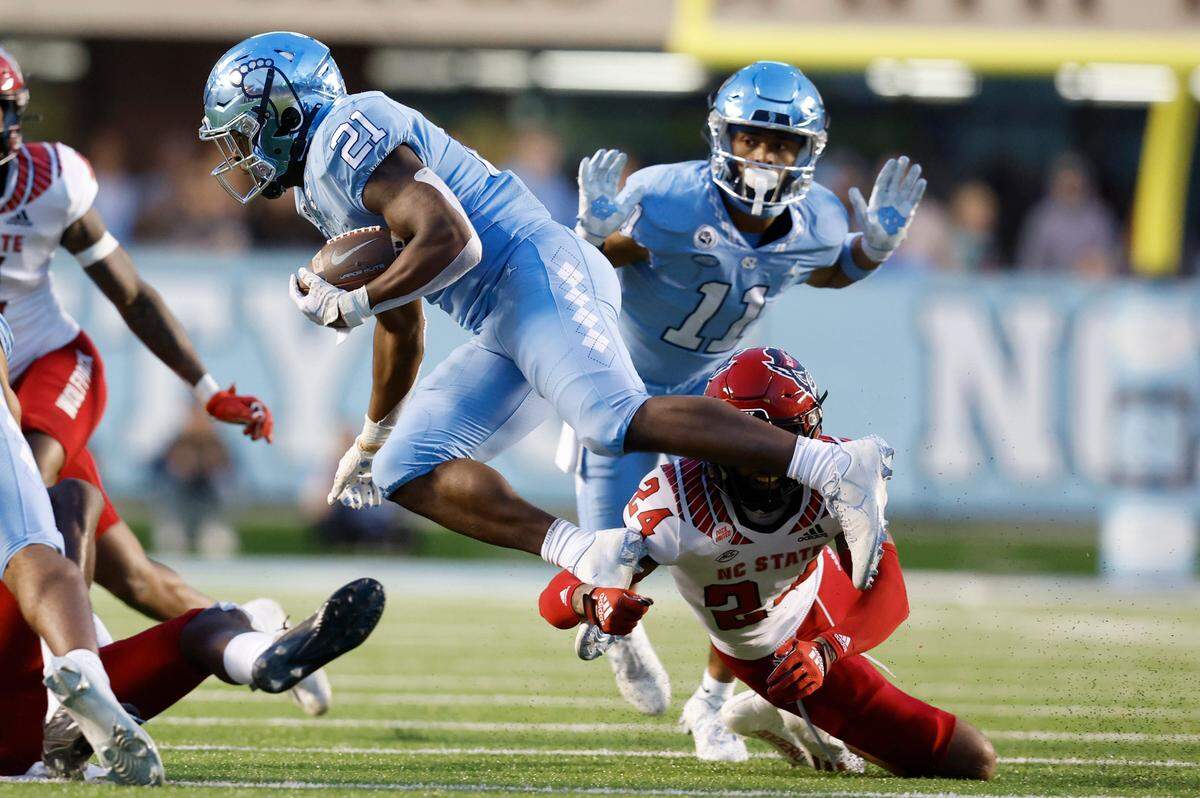 N.C. State cornerback Derrek Pitts Jr. (24) tackles North Carolina running back Elijah Green (21) during the first half of N.C. State’s game against UNC at Kenan Stadium in Chapel Hill, N.C., Friday, Nov. 25, 2022.