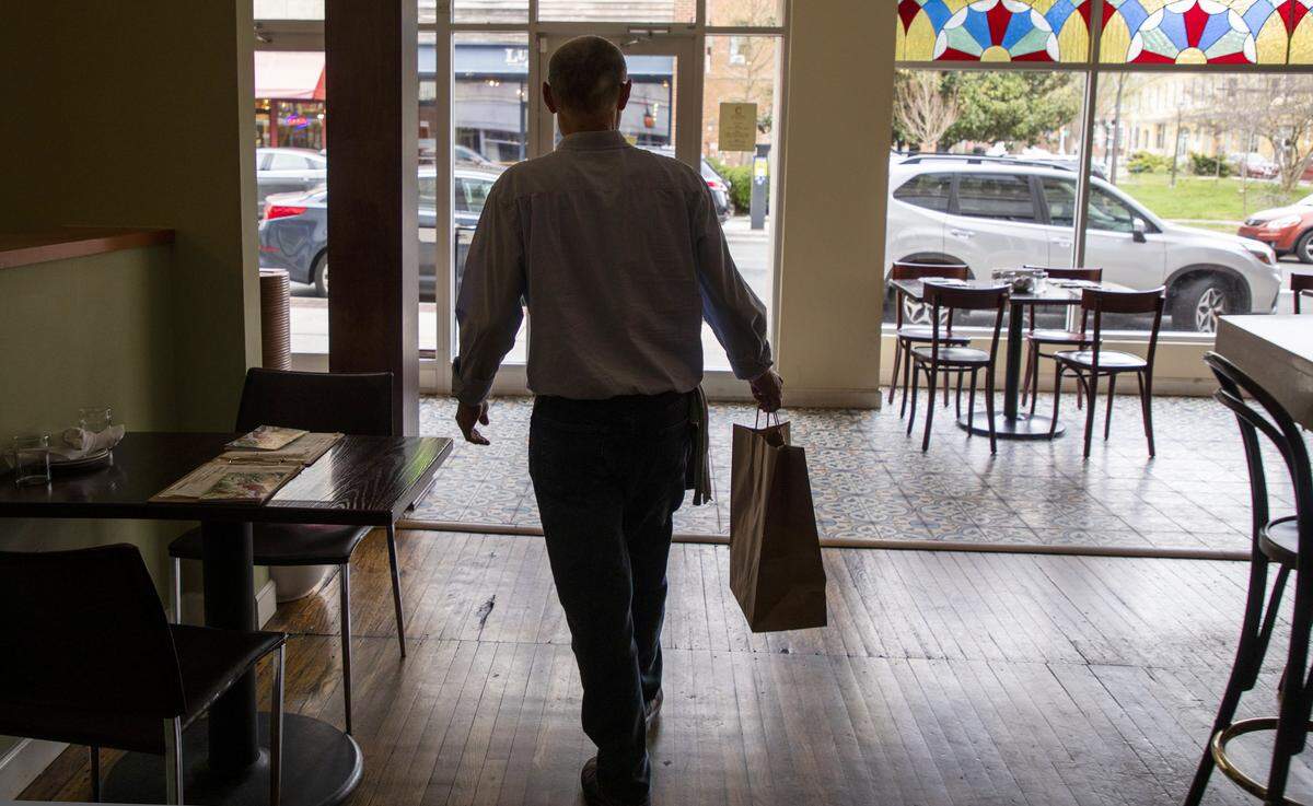 Doug Addington, the head server at Copa, brings a to-go order for a customer to the front as the restaurant practices and trains its staff on the workflow of filling an increasing number of to-go orders and offering curbside service, in response to preventing the spread of COVID-19, on Friday, Mar. 13, 2020, in Durham, N.C.
