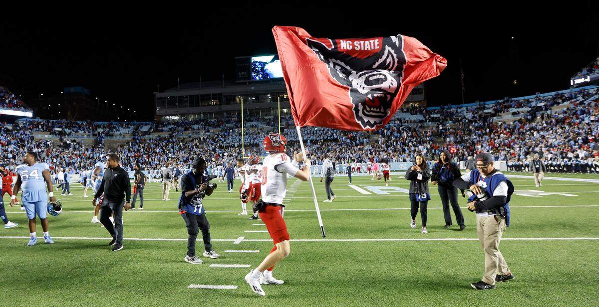 N.C. State quarterback Ben Finley (10) flies the Wolfpack flag after N.C. State’s 30-27 overtime victory over UNC at Kenan Stadium in Chapel Hill, N.C., Friday, Nov. 25, 2022.