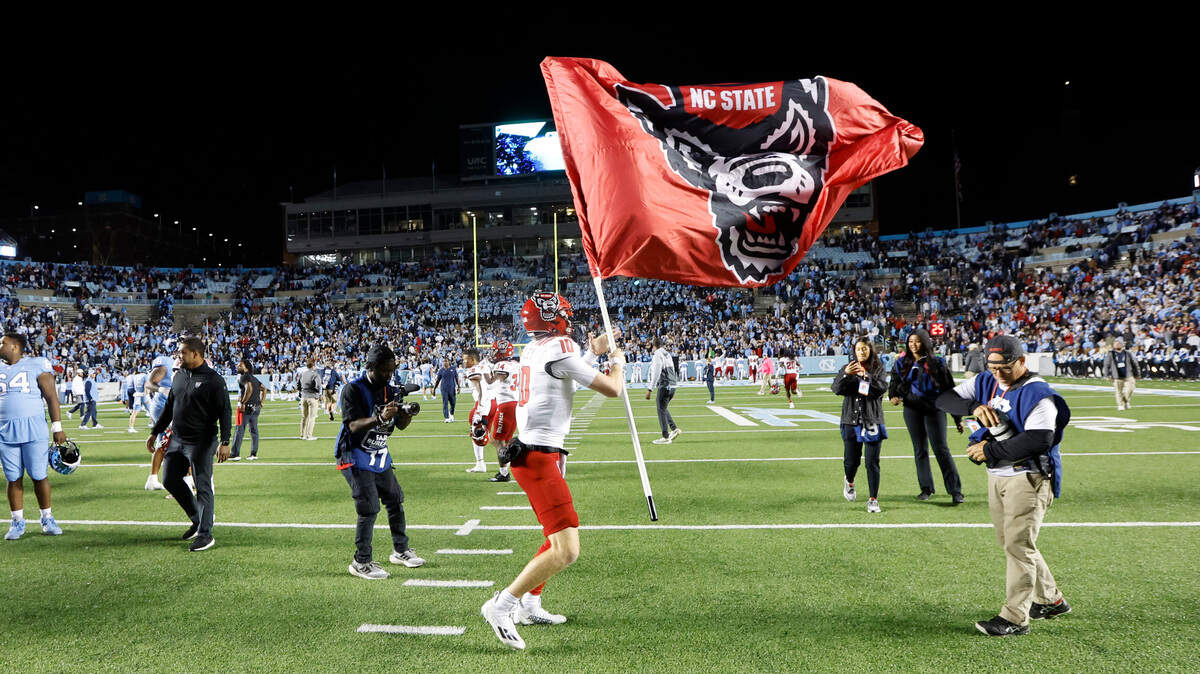 N.C. State quarterback Ben Finley (10) flies the Wolfpack flag after N.C. State’s 30-27 overtime victory over UNC at Kenan Stadium in Chapel Hill, N.C., Friday, Nov. 25, 2022.