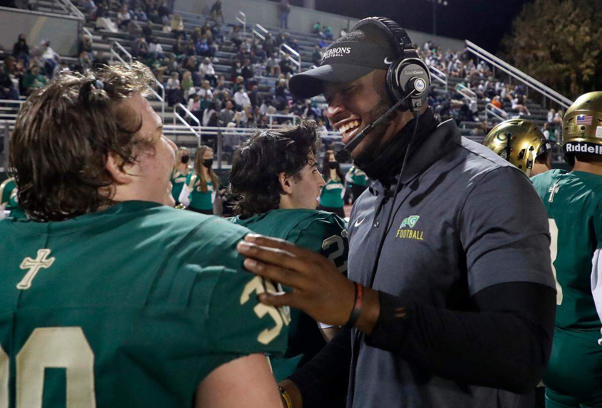 N.C. State linebacker Isaiah Moore celebrates with Cardinal Gibbons High School’s Carter Scearce (30) during the Crusaders’ game against Pine Forest in Raleigh, N.C., Friday, April 16, 2021. Moore is doing a minor at State in coaching. Part of the curriculum required a certain amount of intern hours getting real life coaching experience, which led Moore to volunteer coach at Gibbons this season.