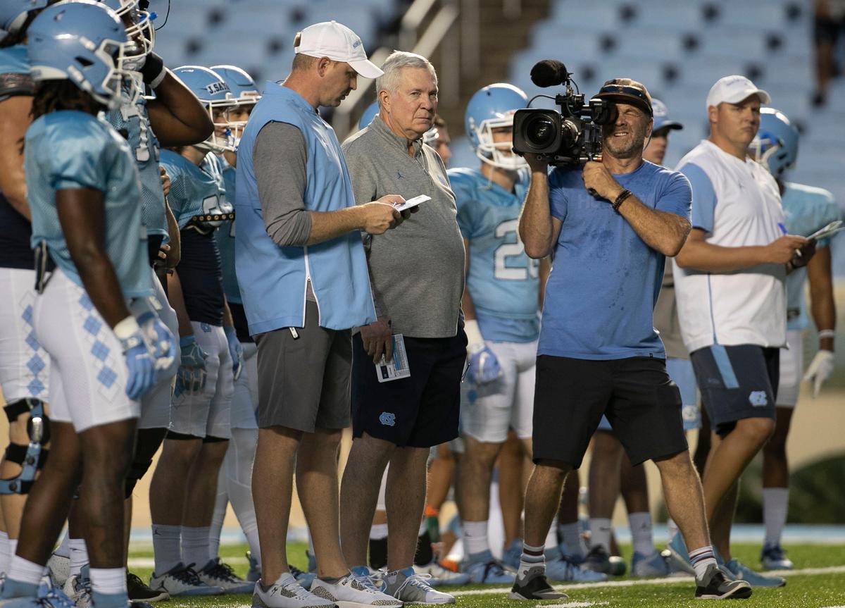 An ESPN videographer works up close to head coach Mack Brown during the Tar Heels’ practice in Kenan Stadium on Monday August 19, 2019 in Chapel Hill, N.C.