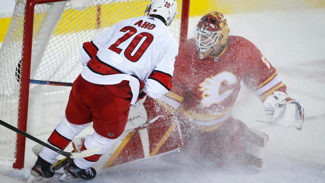 Carolina Hurricanes’ Sebastian Aho, left, scores the on Calgary Flames goalie Jacob Markstrom during overtime in an NHL hockey game Thursday, Dec. 9, 2021, in Calgary, Alberta. (Jeff McIntosh/The Canadian Press via AP)