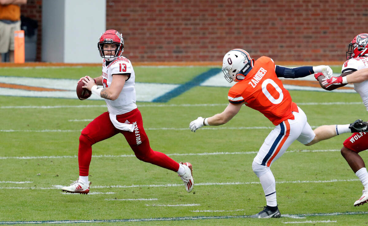 N.C. State quarterback Devin Leary (13) looks for receivers as Virginia linebacker Zane Zandier (0) chases him during the first half of N.C. State’s game against Virginia at Scott Stadium in Charlottesville, Va., Saturday, Oct. 10, 2020.
