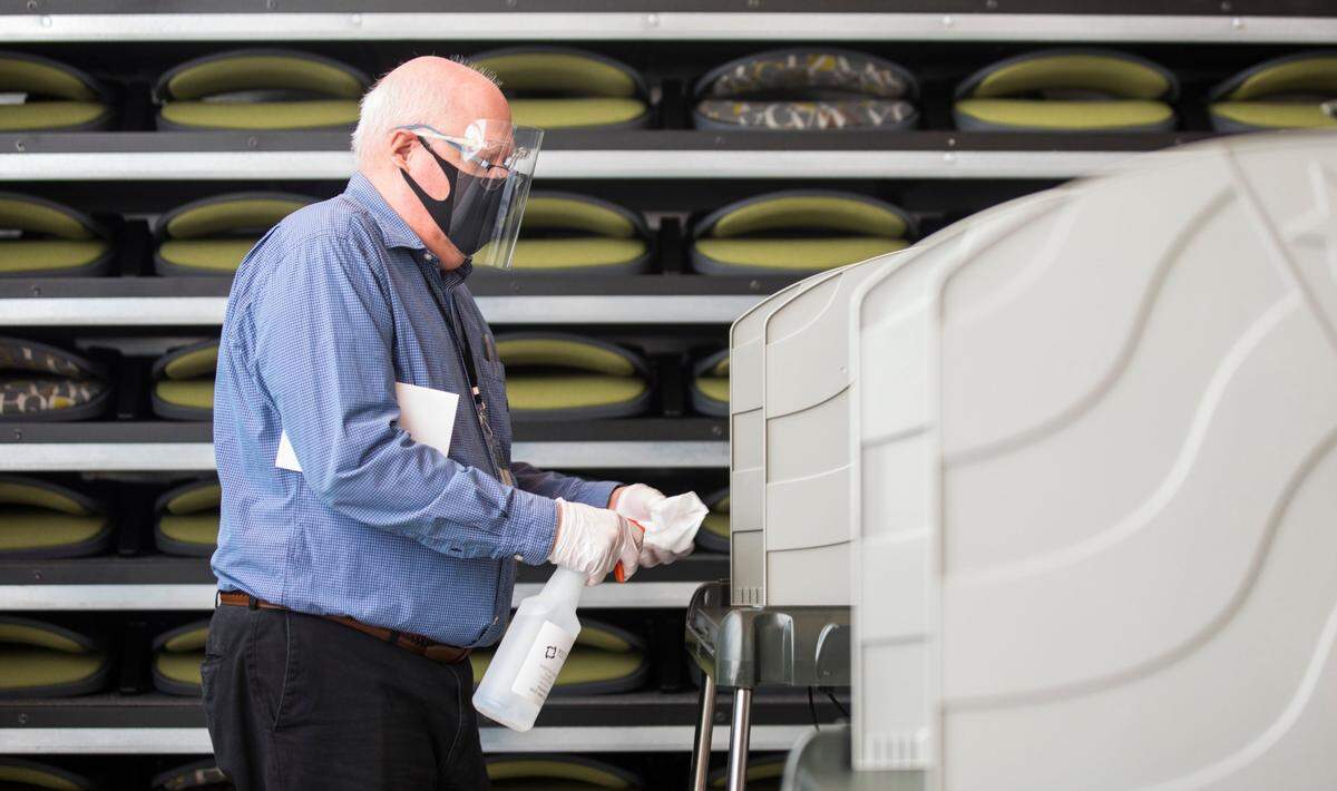 Durham County poll worker John Compton sanitizes a voting both inside the Durham County Main Library in Durham, N.C. on Thursday morning, Oct. 15, 2020, the first day of early voting.