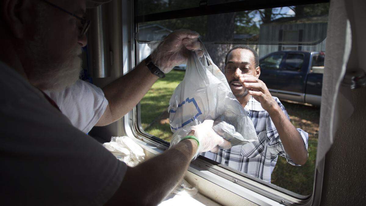 Red Cross volunteer Marty Knight of Momence, Ill., hands Anthony Wooten of New Bern hot meals from their Red Cross truck in the Redwood Terrace Mobile Home Park in New Bern, N.C. on Wednesday morning September 19, 2018. The meals were prepared by the North Carolina Baptist Men.