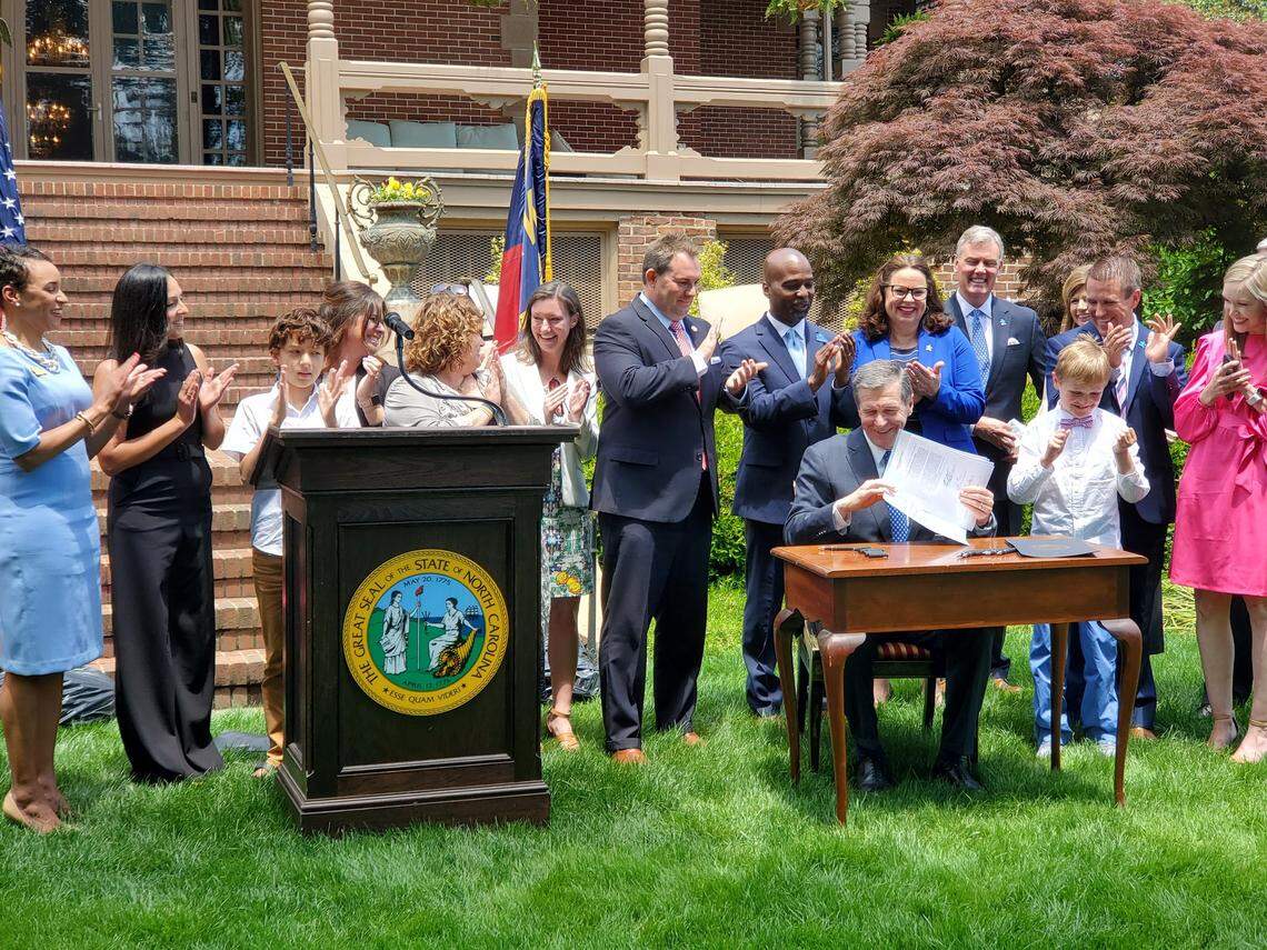 N.C. Gov. Roy Cooper signs Senate Bill 103, which establishes a licensure process for behavior analysts, into law on the grounds of the Executive Mansion on Monday, May 17, 2021. Cooper was flanked by lawmakers and families of children with autism who benefit from the new law.