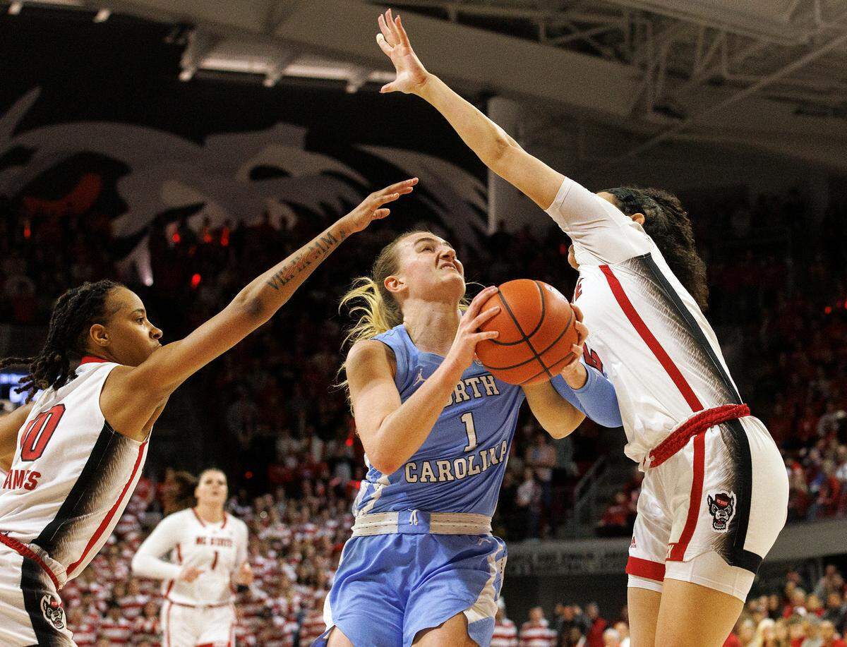 North Carolina’s Alyssa Ustby drives to the basket between N.C. State’s Aziaha James and Mimi Collins during the first half of the Wolfpack’s game on Thursday, Feb. 1, 2024, at Reynolds Coliseum in Raleigh, N.C.