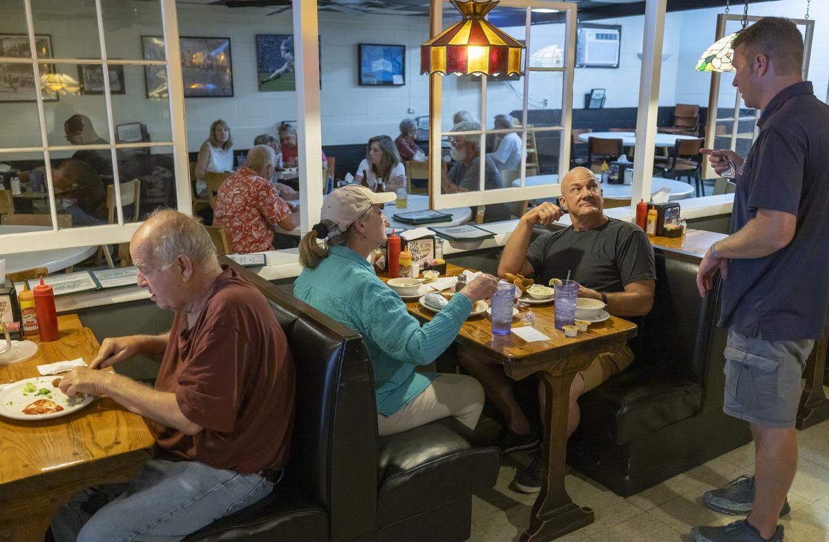 Customers Hugh Harrington and his wife Joy Harrington talk with Virlie’s Grill owner Kain Whitaker on Thursday July 10, 2025 in downtown Pittsboro, N.C. 