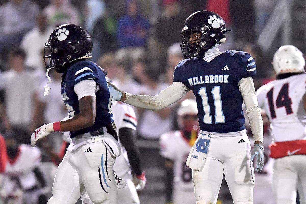 Millbrook strong safety Cairo Williams (11) congratulates defensive back Malcolm McIntyre (16) before the down against Jordan during a first half. The Millbrook Wildcats and the Jordan Falcons met in the third round of the NCHSAA 8A football playoffs in Raleigh, N.C. on November 21, 2025.