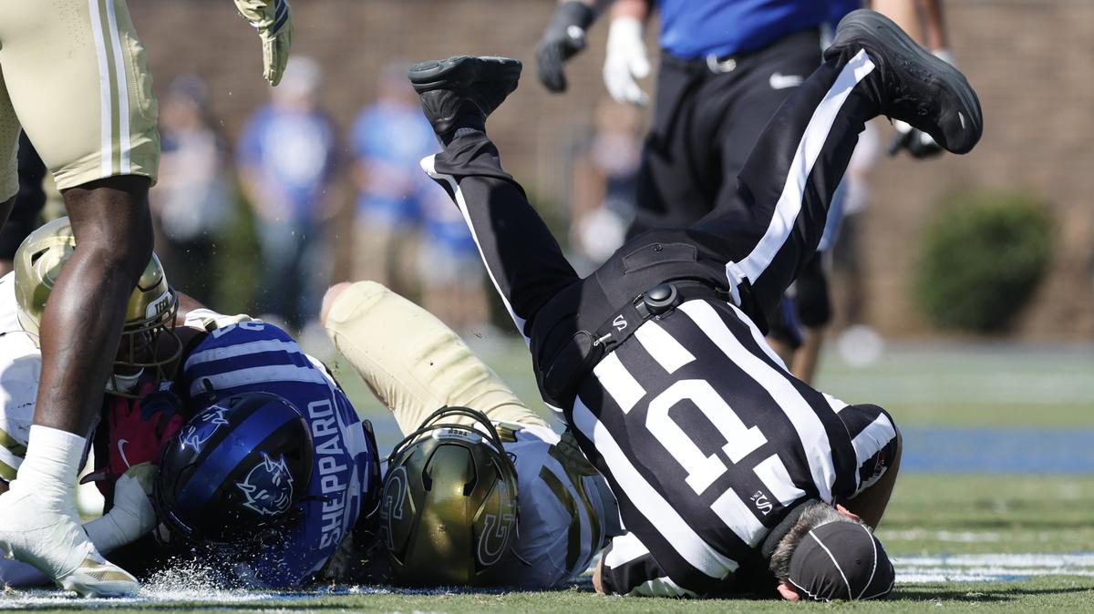 Umpire Danny Worrell goes into the turf as Duke’s Nate Sheppard (20) is tackled during the first half of Duke’s game against Georgia Tech at Wallace Wade Stadium in Durham, N.C., Saturday, Oct. 18, 2025.