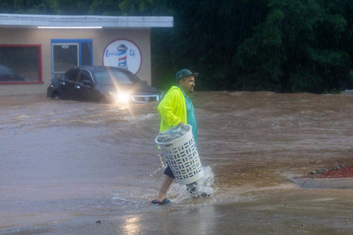 A laundromat patron wades through fast moving water that flooded Pittsboro Elementary School Road, engulfing the Laundry Land laundromat and the Leveled Up barbershop as Tropical Storm Chantal moved across the Triangle causing flash flooding on Sunday, July 6, 2025 in Pittsboro, N.C.