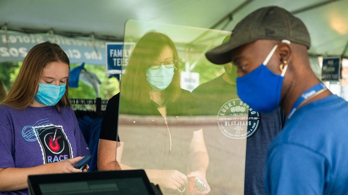 Denise Tripp, center, buys Duke-branded clothing from a store set up under a tent outside before moving her daughter Maggie Tripp, left, into her dorm room where she will live for her first year at Duke University, on Friday, Aug. 7, 2020, in Durham, N.C.