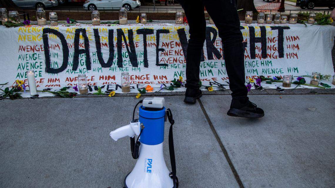 Demonstrators leave flowers, candles and air fresheners on a banner during a vigil for Daunte Wright and others killed by police Sunday, April 18, 2021 in Moore Square.