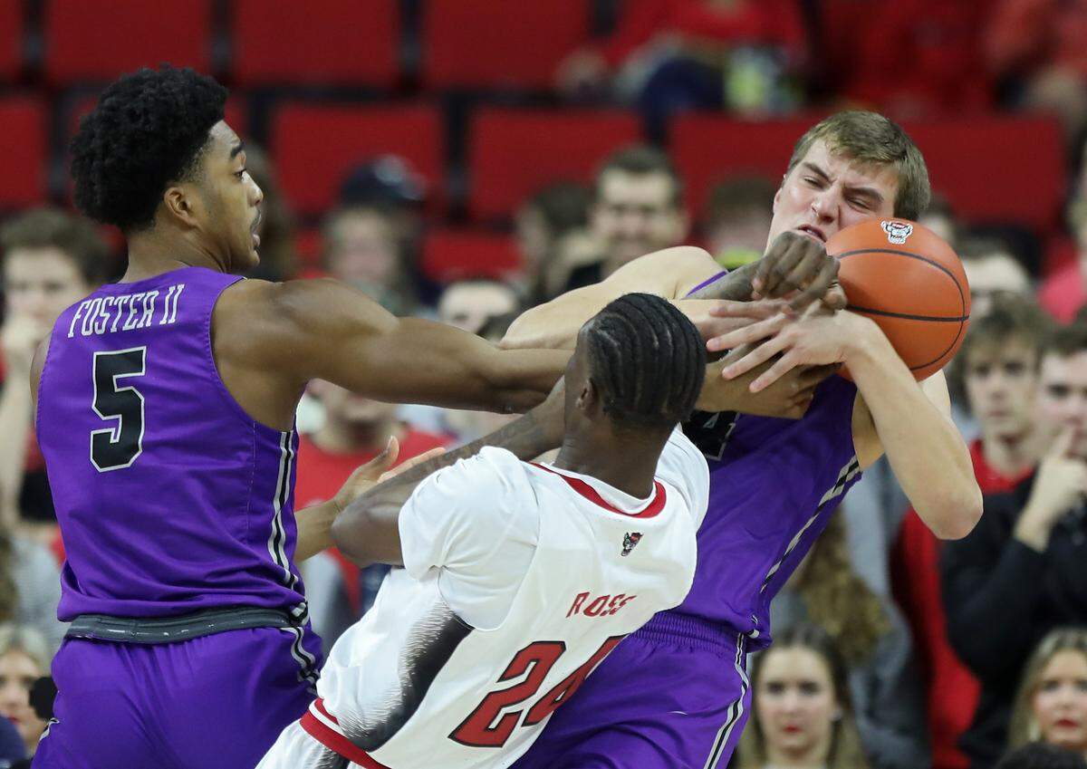 North Carolina State’s Ernest Ross fights for possession with Furman’s Marcus Foster and Ben VanderWal during the first half of a men’s basketball game at PNC Arena on Tuesday, Dec. 13, 2022, in Raleigh, N.C.