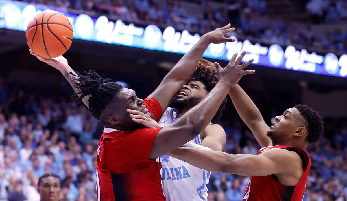 North Carolina’s R.J. Davis (4) is fouled as he is defended by N.C. State’s D.J. Burns Jr. (30) and Casey Morsell (14) during the first half of N.C. State’s game against UNC at the Smith Center in Chapel Hill, N.C., Saturday, Jan. 21, 2023.