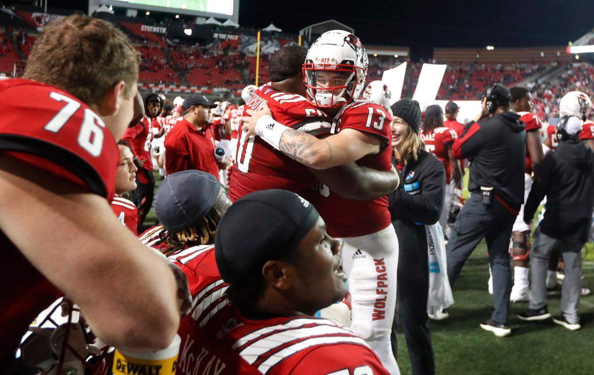 N.C. State quarterback Devin Leary (13) hugs center Grant Gibson (50) late in the second half of N.C. State’s 28-13 victory over Louisville at Carter-Finley Stadium in Raleigh, N.C., Saturday, October 30, 2021.