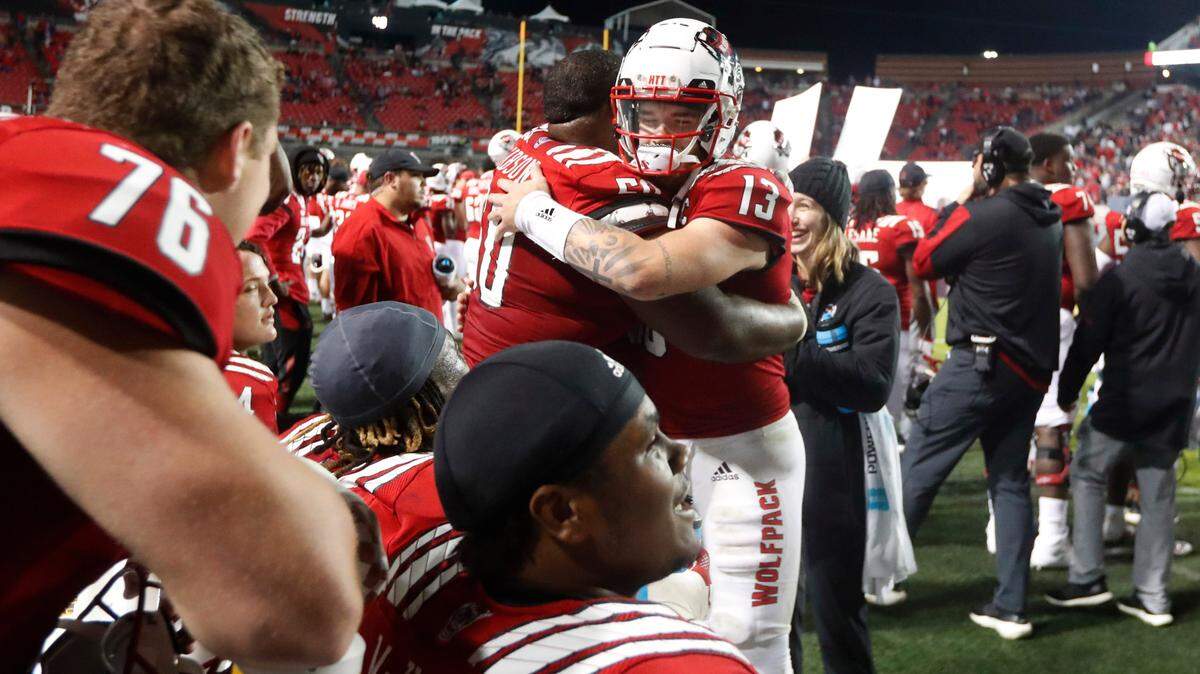 N.C. State quarterback Devin Leary (13) hugs center Grant Gibson (50) late in the second half of N.C. State’s 28-13 victory over Louisville at Carter-Finley Stadium in Raleigh, N.C., Saturday, October 30, 2021.