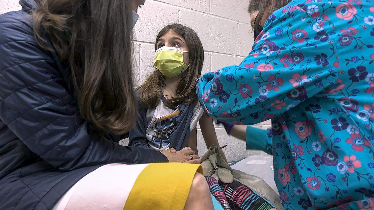 Alejandra Gerardo, 9, looks up to her mom Dr. Susanna Naggie as she gets the first of two Pfizer COVID vaccinations during a clinical trial for children at Duke Health earlier this year.