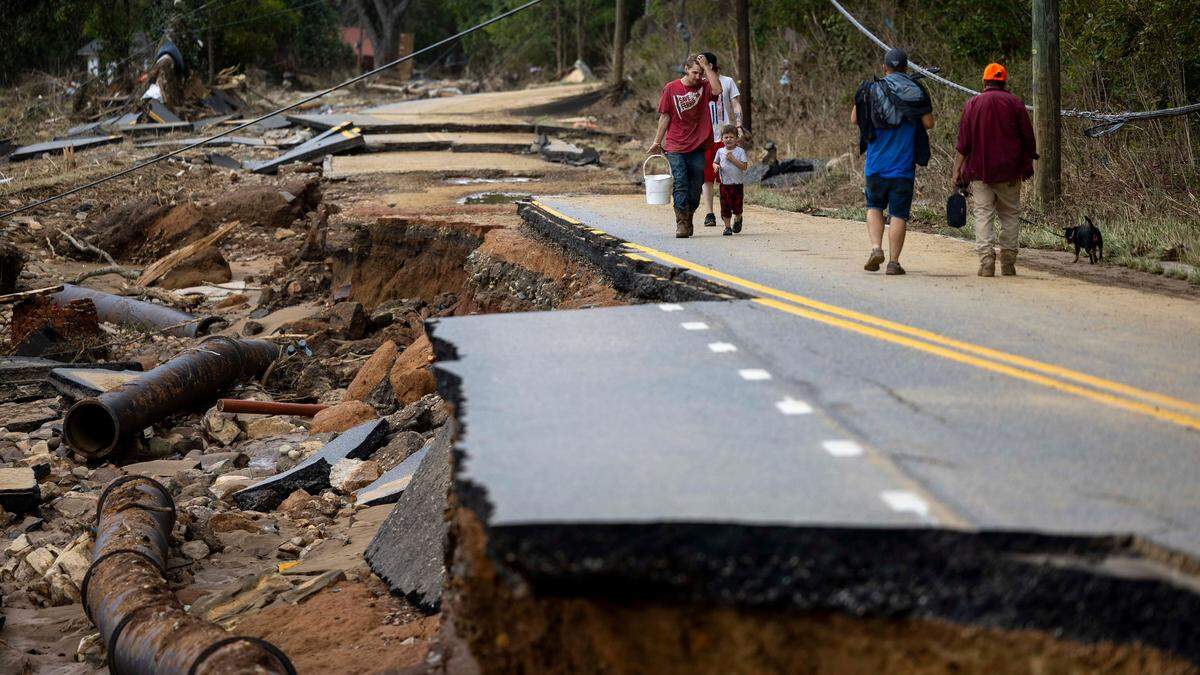 Swannanoa residents walk through devastating flood damage from the Swannanoa River on Sunday, Sept. 29, 2024. The remnants of Hurricane Helene caused widespread flooding, downed trees, and power outages in western North Carolina.