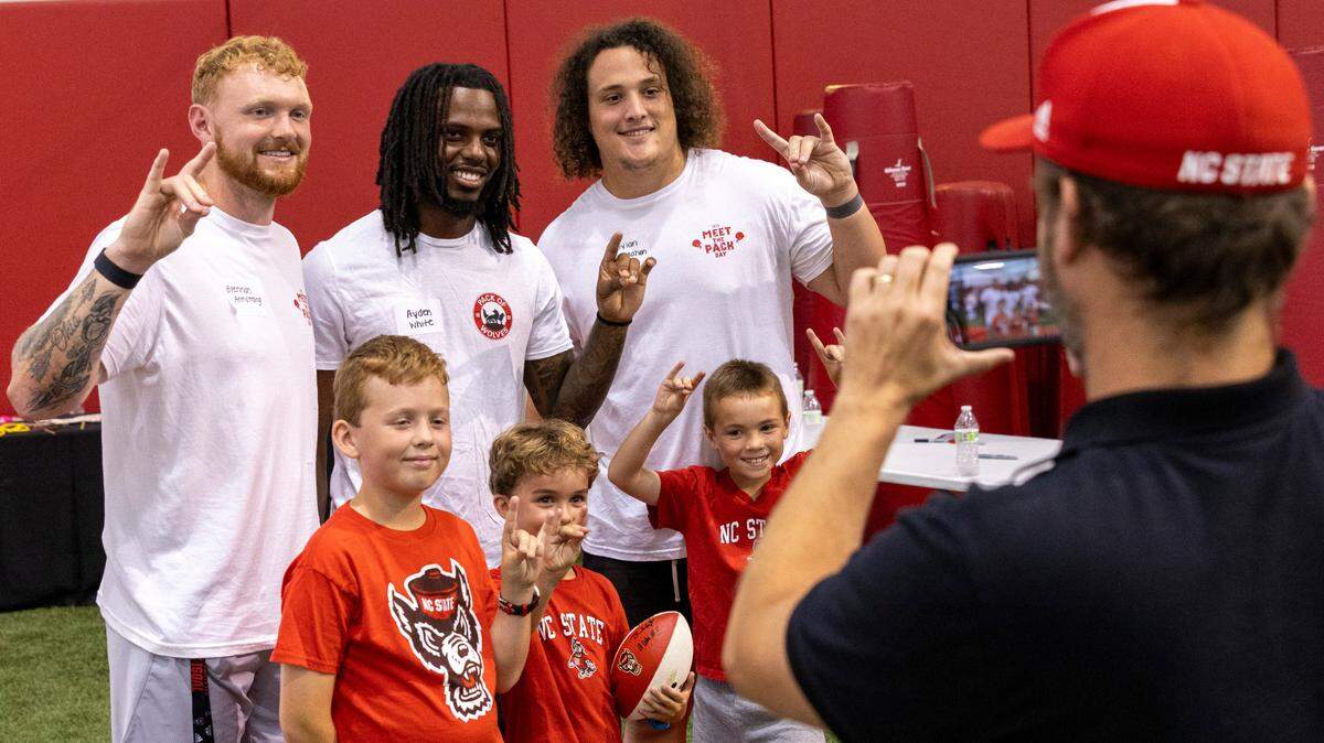 From left, N.C. State’s Brennan Armstrong, Ayden White,and Dylan McMahon pose with fans during a ‘Meet the Pack’ event at the Close-King Indoor Practice Facility Saturday, Aug. 16, 2023.