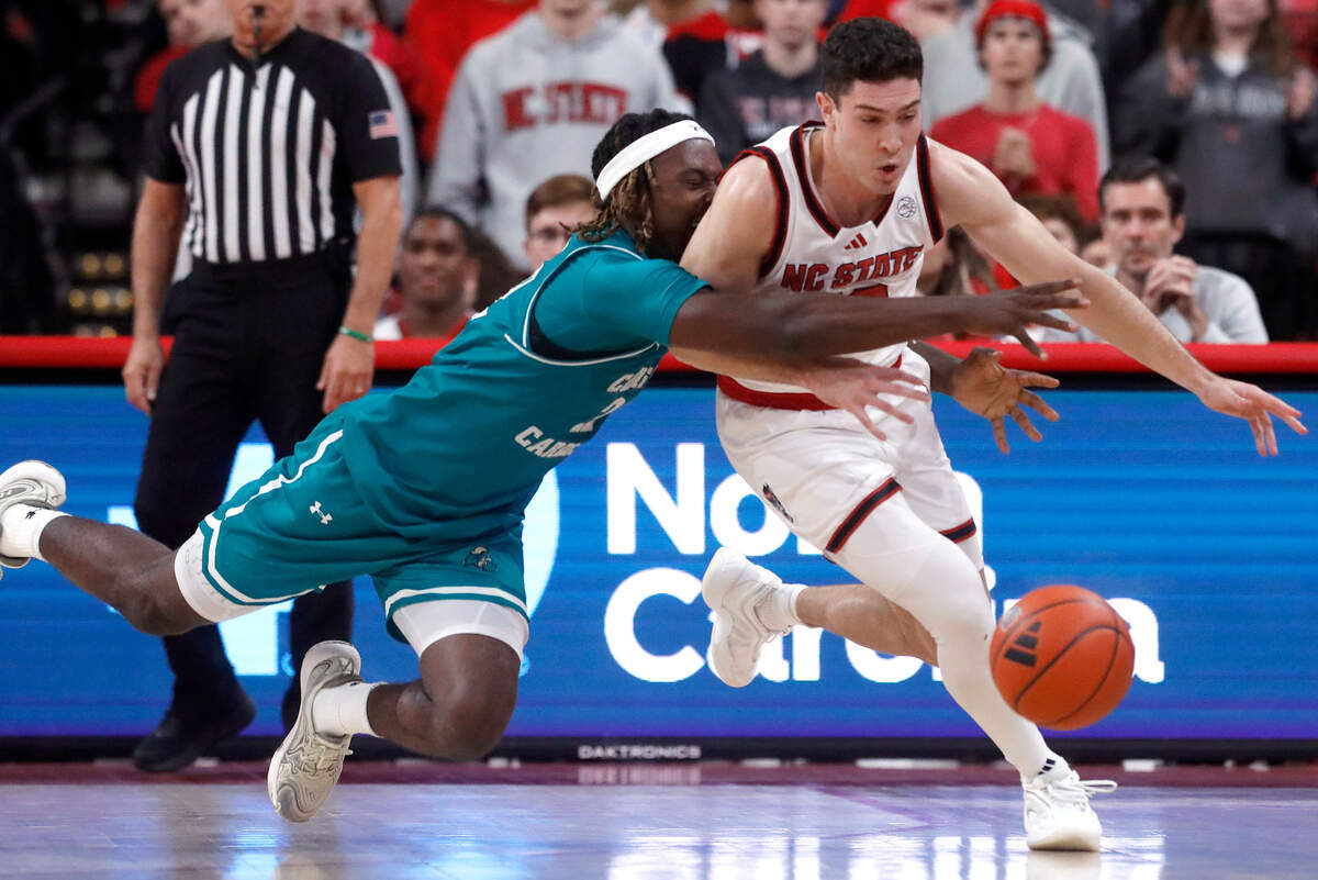 Coastal Carolina’s Denzel Hines and N.C. State’s Michael O’Connell sprint towards a loose ball during the second half of the Wolfpack’s 82-70 win on Wednesday, Nov. 13, 2024, at Lenovo Center in Raleigh, N.C.