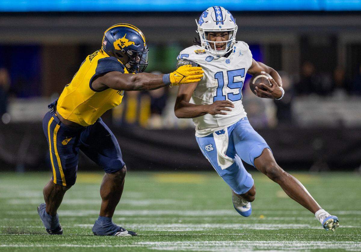 North Carolina quarterback Conner Harrell (15) looks for running room on a 11-yard carry in the second quarter against West Virginia’s Lee Kpogba (1) on Wednesday, December 27, 2023 at Bank of American Stadium in Charlotte, N.C.