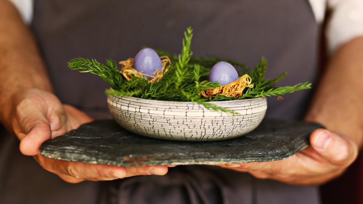 Herons’ executive chef Steven Devereaux Greene holds pickled quail eggs, dyed Easter egg purple, that are served in edible nests inside a wooden bowl lined with conifer twigs. They are part of a series of amuses-bouches in Herons’ eight-course tasting menu called “The Art Tour.”
