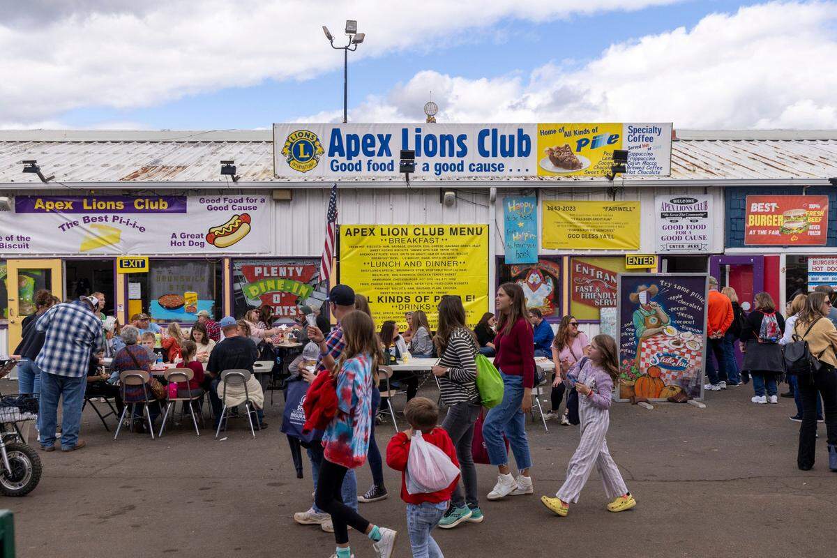 Fair-goers walk past the Apex Lions Club restaurant during the State Fair in Raleigh Monday, Oct. 16, 2023. The Apex Lions Club has been serving food at the fair’s restaurant row since 1943. The restaurant row building will be replaced with an events center next year.