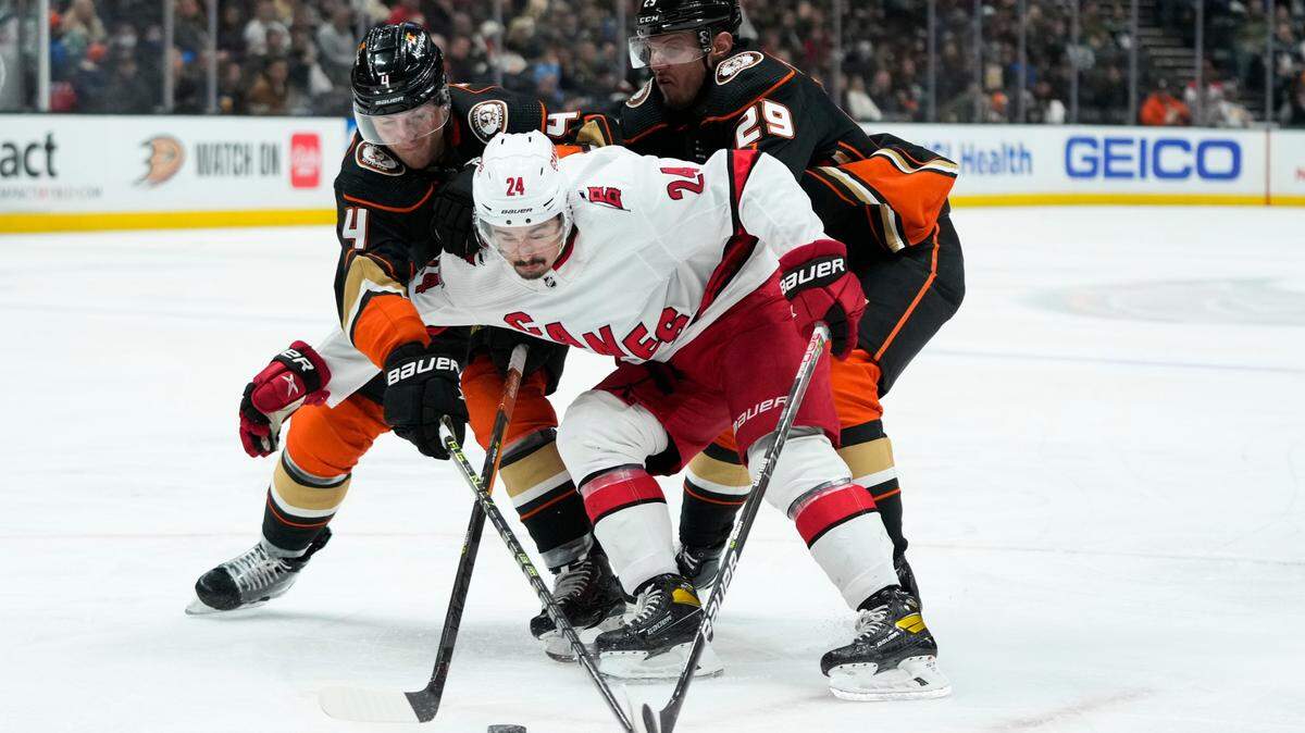 Carolina Hurricanes’ Seth Jarvis (24) is double-teamed by Anaheim Ducks’ Cam Fowler (4) and Dmitry Kulikov (29) during the second period of an NHL hockey game Tuesday, Dec. 6, 2022, in Anaheim, Calif. (AP Photo/Jae C. Hong)