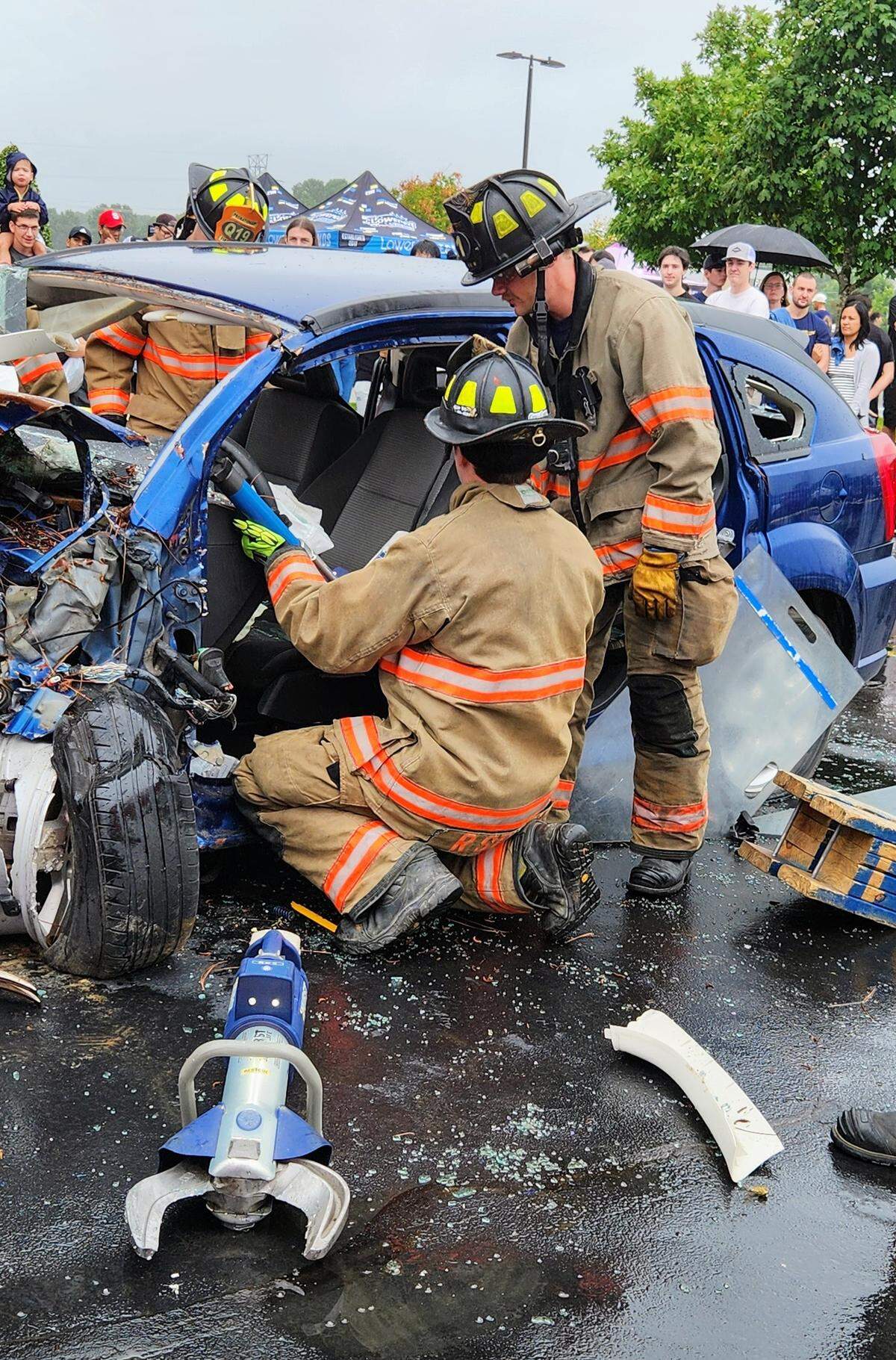 Firefighers take apart a blue car.