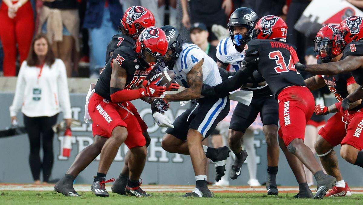 N.C. State cornerback Tamarcus Cooley (15) strips the ball from Duke wide receiver Eli Pancol (4) during the first half of N.C. State’s game against Duke at Carter-Finley Stadium in Raleigh, N.C., Sat. Nov. 9, 2024.