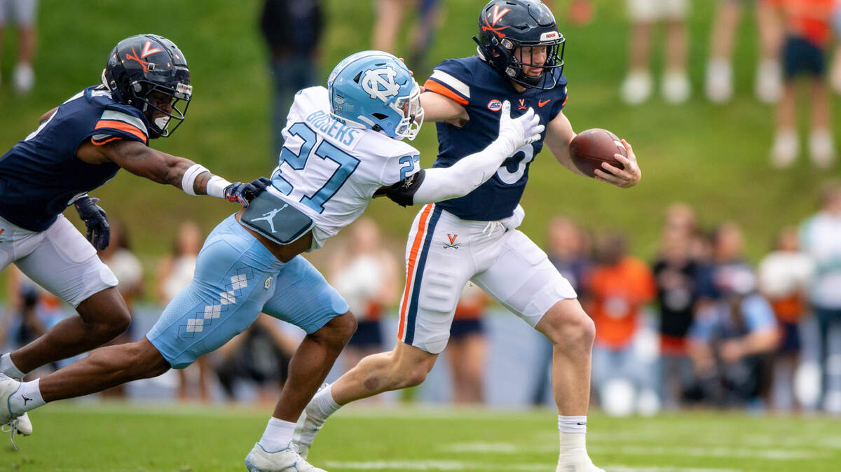 Virginia quarterback Brennan Armstrong (5) stiff-arms North Carolina defensive back Giovanni Biggers (27) during the first half of an NCAA college football game on Saturday, Nov. 5, 2022, in Charlottesville, Va. (AP Photo/Mike Caudill)