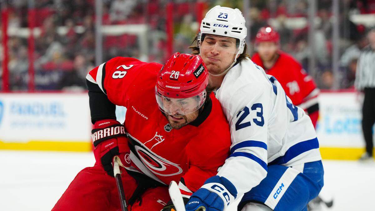 Apr 13, 2025; Raleigh, North Carolina, USA; Carolina Hurricanes left wing William Carrier (28) and Toronto Maple Leafs left wing Matthew Knies (23) battle during the first period at Lenovo Center. Mandatory Credit: James Guillory-Imagn Images
