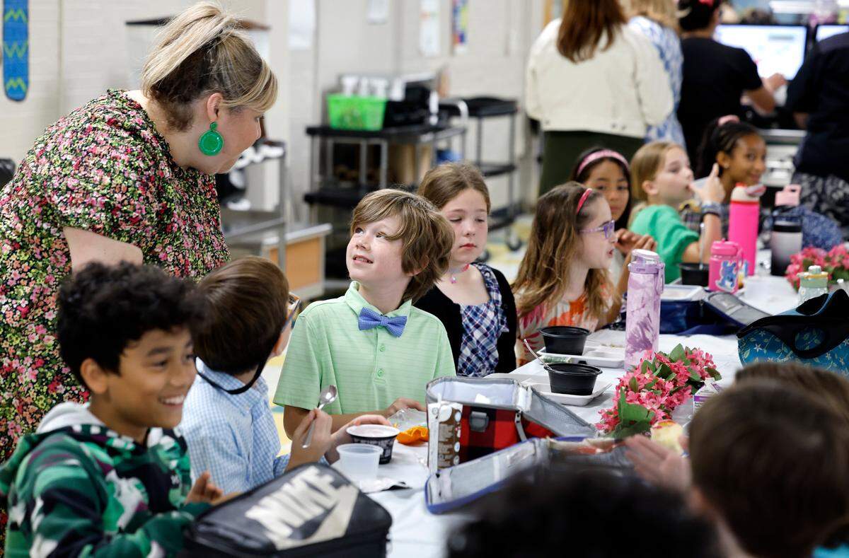Combs Elementary School’s Traci Totherow talks with fourth grader Winston Eckerson during the Silver Tray lunch at Combs Elementary School in Raleigh, N.C., Thursday, May 16, 2024. At the Silver Tray Luncheon there is fancy silverware, cafeteria tables have tablecloths and centerpieces as the Enloe High School orchestra plays music to provide a fine dining experience. The dining experience was the culmination of a year-long effort to teach Combs’ students about the value of social etiquette and good manners.