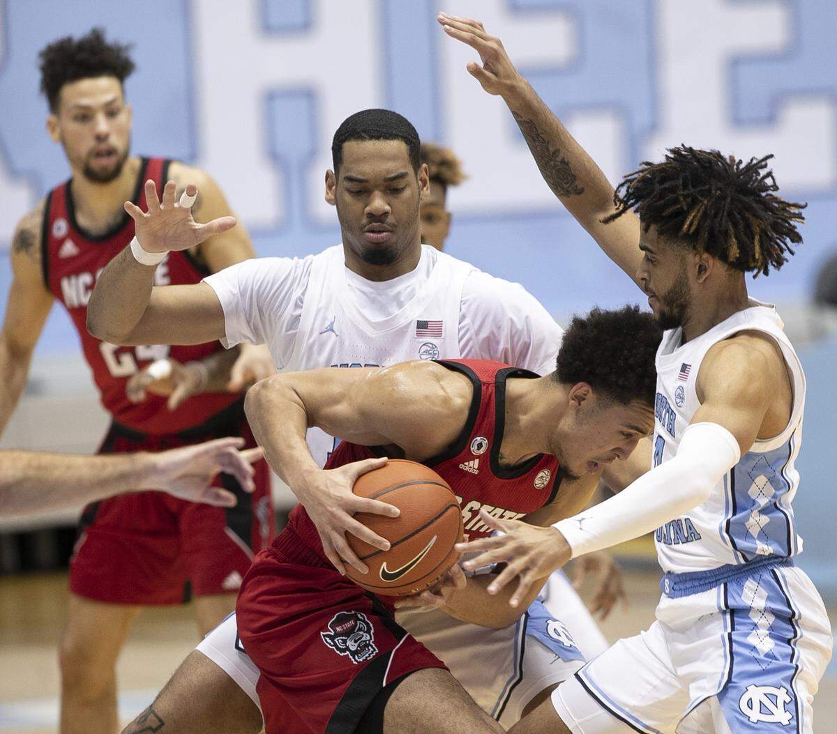 N.C. State’s Jericole Hellems (4) is trapped by North Carolina’s Garrison Brooks (15) and R.J. Davis (4) in the first half on Saturday, January 23, 2021 at the Smith Center in Chapel Hill, NC.