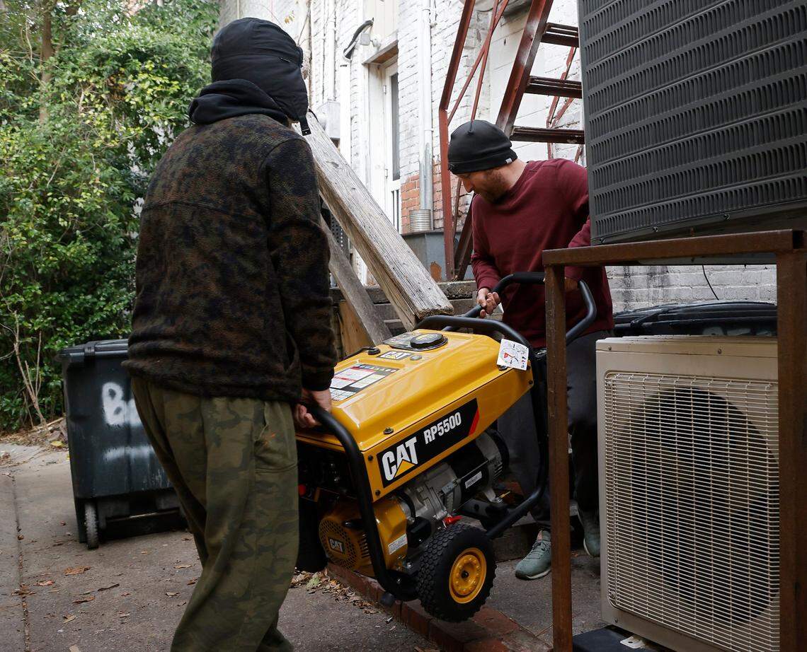 Brothers Tom and Derek Markey carry a portable generator outside of Betsy’s Crepes restaurant on Monday, Dec. 5, 2022, in Southern Pines, N.C. Tom Markey, an employee at the business, said the generator was purchased a few years ago for power outages due to severe weather, but this is its first use.